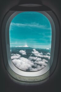 janela de avião com vista para céu azul e nuvens brancas